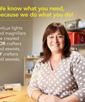 Woman in a crafting room with ViviLux product slogan on wall behind her; Pro Grade Optical 3X Magnifier With Handi-Clip visible on table.