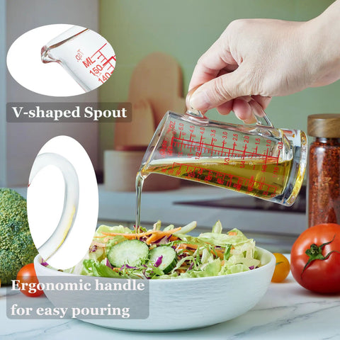 Hand pouring liquid from Glass Measuring Cup 5 Oz 150 Ml Shot Glass With V Spout And Insulated Handle onto salad