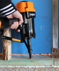 PSSCP 3 Inch Pneumatic Single Pin Concrete Nailer with case in use, fastening wood to concrete in a basement framing project.