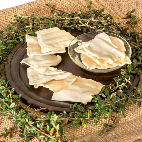 Image of American Beefhide Chips Dog Chew Treats Natural Flavor 32 Oz Long Lasting Rawhide Chews for Strong Chewers on a plate.