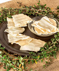 Beefhide Chips Dog Chew Treats Natural Flavor 22 Oz displayed on a dark tray with greenery, premium quality rawhide chews made in USA.