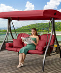 Woman reading on a 3 In 1 Outdoor Porch Swing With Adjustable Canopy For Adults, Cozy 3 Seat Patio Swing With Thick Cushions, Pillows And Cup Holders, Wine Red, Great For Backyard, Porch Or Garden, Easy Setup And Durable Design