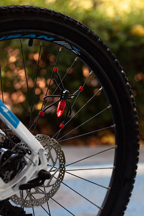 Close-up of a bicycle wheel with Totally Sick Spider Bike Wheel Spoke Lights LED Glow For Night Rides, showing red spider lights
