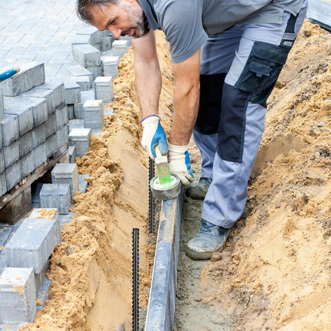 Worker using twenty pack of 24 inch straight rebar stakes with one half inch diameter steel for heavy duty ground anchors in landscaping