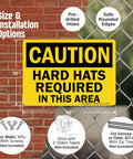 Caution Hard Hats Required In This Area Sign 10 By 14 Inch Aluminum Black On Yellow Durable Outdoor Safety Sign With Four Corner Mount Holes For Easy Installation Jobsite Safety Sign shown on a fence grid.