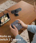 Plug And Play 1080P HD Webcam Packs Dual Noise Killing Mics And Wide Angle Lens With Privacy Sliding Cover For Zero Lag Business Calls And Buttery Smooth Live Broadcasting Sessions on a desk with a gaming console.