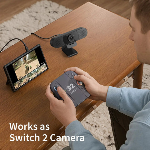 Plug And Play 1080P HD Webcam Packs Dual Noise Killing Mics And Wide Angle Lens With Privacy Sliding Cover For Zero Lag Business Calls And Buttery Smooth Live Broadcasting Sessions on a desk with a gaming console.