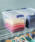 27 Quart Medium Clear Plastic Storage Bin With Heavy Duty Latching Lid And Sturdy Handles For Garage And Closet Organization stacked with folded clothes.