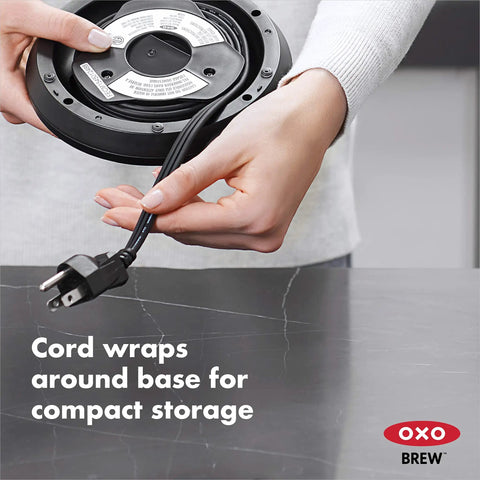 Person wrapping cord around base of Cordless Glass Electric Kettle With 1.75 Liter Capacity Borosilicate Glass For Pure Taste LED Power Indicator Auto Shutoff When Boiling Slow Release Lid For Steam Durable Quick Boil Easy Pour No Mess for compact storage.