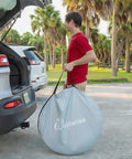 Person carrying Pop Up Beach Tent Sun Shelter With UPF50+ UV Protection bag next to car