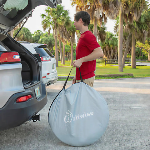 Person carrying Pop Up Beach Tent Sun Shelter With UPF50+ UV Protection bag next to car