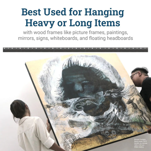 Two people using Beefy Heavy Duty French Cleat Hanger 45 Inch System to mount large framed picture securely on wall