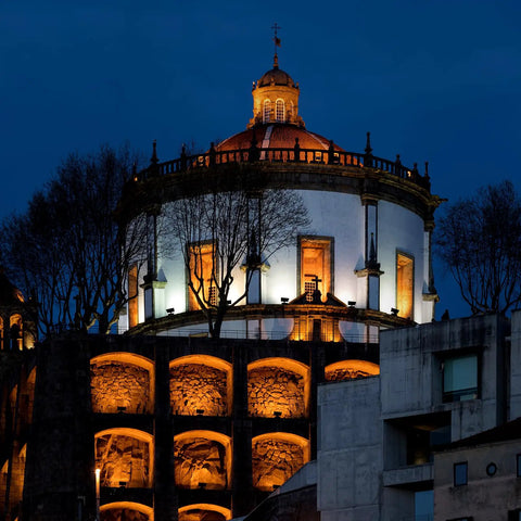 Illuminated historic building at night with trees, showcasing architectural details and lighting effects.