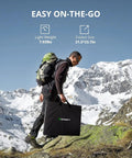 Man hiking with 200W Portable Solar Panel For Power Station With Foldable Design And Adjustable Kickstands against snowy mountains.