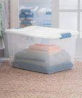 64 Quart Clear Latching Storage Box with White Lid, shown storing folded blankets, ideal for home and dorm organization.