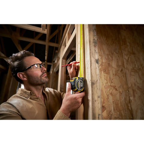 Person using Fatmax Autolock Tape Measure 8m Metric Only Yellow Black, Reverse Lock For One-Handed Control on wooden structure