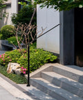 Heavy Duty Adjustable Stair Handrail Rock Solid Wall And Floor Mounted Wrought Iron Safety Rail Built Tough For One To Three Steps No Sweat Installation In Matte Black Steel on outdoor steps with lush landscaping.