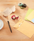Super Hold Tape With 50 Percent More Adhesive, Clear Finish, 2 Rolls on desk with envelopes and coffee mug