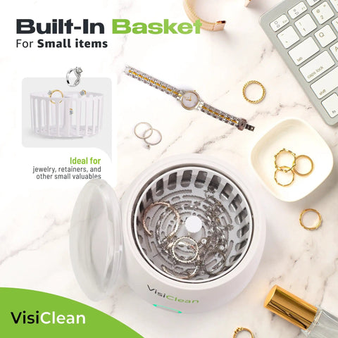 Ultrasonic Retainer Cleaner with built-in basket for jewelry and small items, surrounded by jewelry pieces on a marble surface.