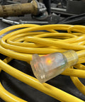 Heavy Duty 12/3 Gauge 100-Foot Extension Cord With Power Indicator Light, Kink-Resistant SJTW Indoor Outdoor Yellow coiled on workbench