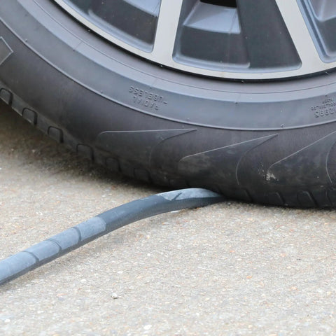 Heavy Hitter Air Compressor Hose Three Eighth By Fifty Feet Hybrid Line visible beneath a tire on a concrete surface.