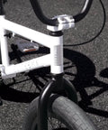 Close-up of white BMX freestyle bike with durable steel frame in 20 inch size, built for stunts and daily cruising.