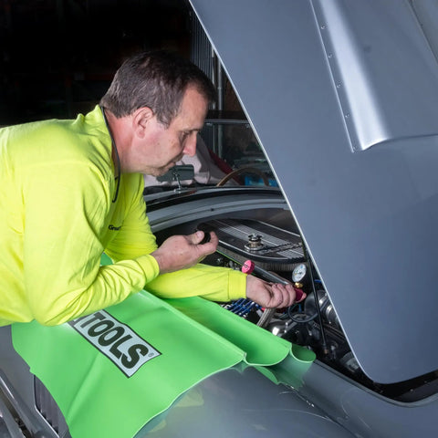 Mechanic using Universal Cooling System Adapter Kit for Radiator Pressure Testing on car engine, fits plastic reservoirs.