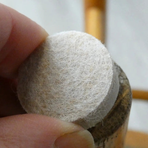 Applying a 1 Inch Round Self Adhesive Felt Furniture Slider for Hard Floors Leveling Pads to a chair leg to stop scratches