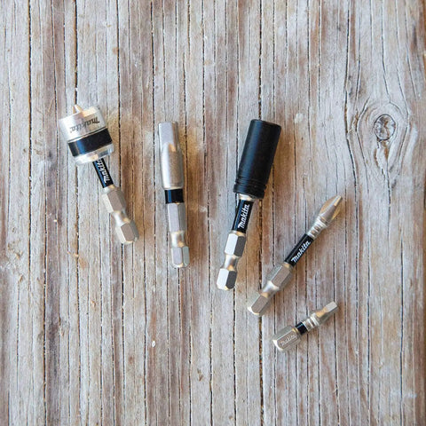 Assorted impact driver bits on wood surface, including Impact XPS No 2 Phillips 2 Inch Power Bit 15 Pack For Impact Drivers With Precision Tips