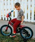 Child riding bike with training wheels on a sidewalk near a white fence, showcasing bicycle tire suitable for 18x2.10 to 18x2.50 sizes.