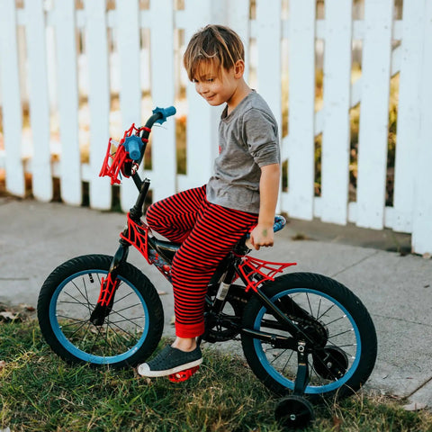 Child riding bike with training wheels on a sidewalk near a white fence, showcasing bicycle tire suitable for 18x2.10 to 18x2.50 sizes.