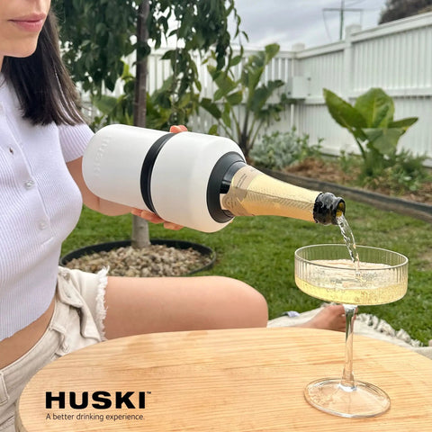 Woman pouring champagne from Next Gen Iceless Wine Chiller Keeps Your Bottle Cold Up To 6 Hours No Ice Needed Fits Champagne Bottles All Stainless Steel The Go To Wine Accessory Perfect Gift For Wine Lovers into a glass outdoors.