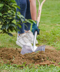 Heavy Duty 43 Inch Round Shovel With Wooden D Handle And Stainless Steel Blade in use for planting shrubs in a garden