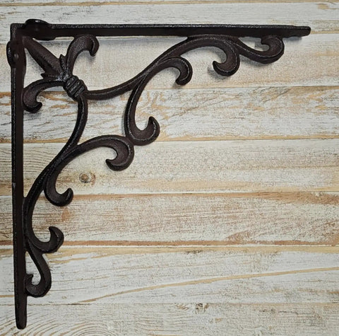 Heavy Duty Cast Iron Shelf Bracket Set With Ornate Fleur De Lis Pattern 10 By 10 Inch Shelf Supports For Sturdy Wall Shelves Classic Decorative Metal Brackets In Satin Brown Finish 8 Count shown against wood backdrop