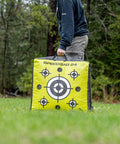 Person carrying Beast 24 Inch Dual Sided Archery Target For 475 FPS Compound Bows And Crossbows in a field.