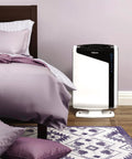 A bedroom scene with an air purifier next to a bed, suitable for Carbon Filters For AeraMax Air Purifier 300 4 Pack That Banish Odors And VOCs While Snagging Big Particles Easy Replace Keeps Your Air Fresh 16.1 By 12.4 By 0.2 In Fits 300 Model.