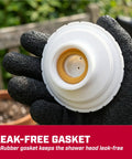 Leak-free white shower head gasket held by hand with glove, background of garden setting.