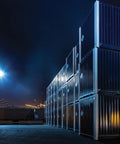 Pro Gear Outdoor LED Floodlight With Slipfitter Mount In Bronze illuminating shipping containers in a nighttime industrial setting.