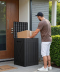 Man placing package in 52 Gallon Outdoor Package Delivery Box With Lockable Lid Heavy Duty Double Wall Resin Construction Perfect Porch Storage Weatherproof Deck Box For Protecting Packages Black Must Have For Busy Couriers And Home Deliveries