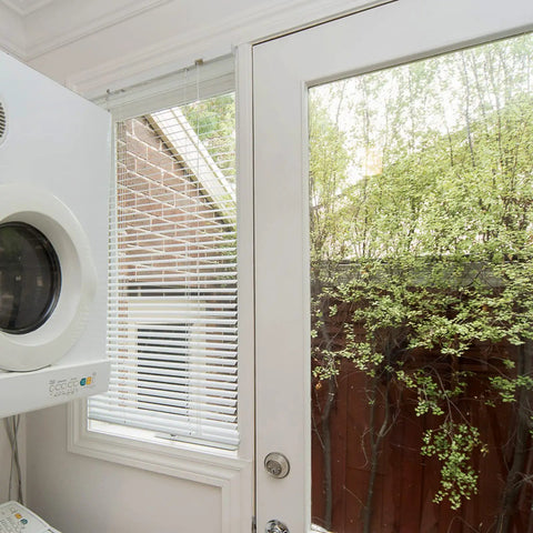 White blinds installed using 2 Inch White Low Profile Box Mount Blind Brackets Bundle, window with a view of backyard greenery.