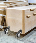 Wooden workbench with Heavy Duty Workbench Casters Kit 600 Lb Capacity Set of 4 attached, in a workshop setting