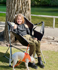 Girl sitting on Heavy Duty 400Lb Portable Hammock Camping Chair With Adjustable Recline, dog nearby, outdoors.