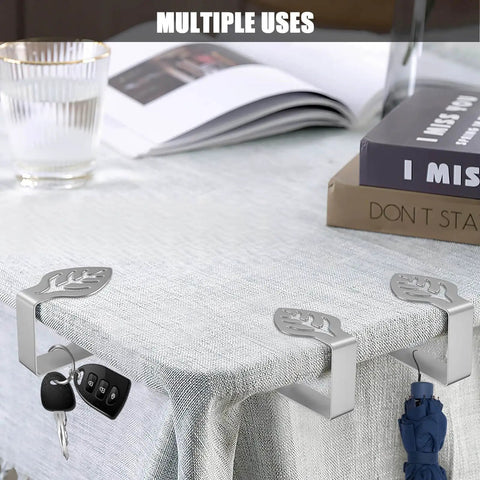 Leaf Shaped Table Cloth Holder Clips 10 Pack Gotta Have Heavy Duty Stainless Steel Outdoor Clip Set For Windy Picnics And Parties Keeps Tablecloth In Place At Weddings Camping RVs And Restaurants, shown securing a tablecloth with keys and an umbrella attached.