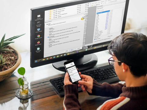 Person using a smartphone and computer on a desk, running data recovery software for Bootable USB Repair Kit For Windows PCs.