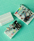 Six Pack 400 Point Solderless Breadboard Kit for Arduino Projects with assembled circuits and color-coded layout on green grid paper