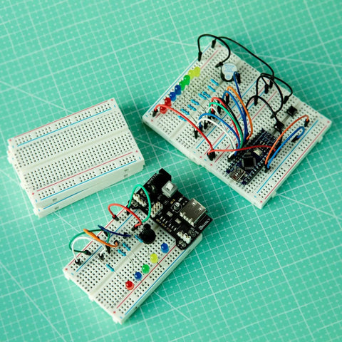 Six Pack 400 Point Solderless Breadboard Kit for Arduino Projects with assembled circuits and color-coded layout on green grid paper