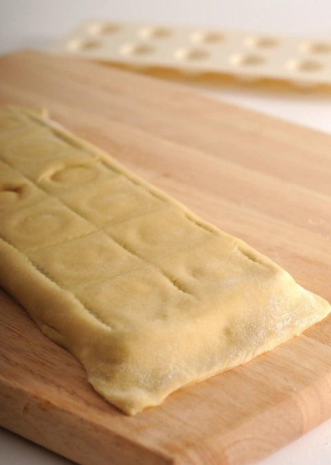 Ravioli Maker With Press 12 Inch Mold For Homemade Pasta No Roller Needed. Pressed dough on wooden board showing ravioli shape.