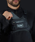 Person wearing water resistant running vest chest pack with phone holder, showing storage and water droplets on fabric.