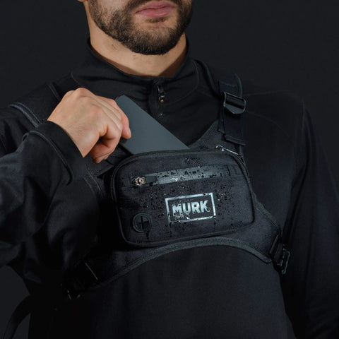 Person wearing water resistant running vest chest pack with phone holder, showing storage and water droplets on fabric.