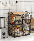 Keep Your Counters Tight With This Solid Stackable Wire Basket Set Designed To Sweep Up Kitchen Clutter While Offering Plenty Of Room For Sorting Fresh Produce Spices And Snacks, showcasing two black wire baskets with wood tops on a kitchen countertop.